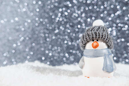 Christmas panorama background. Happy cute penguin in a winter hat on snowdrifts in the light of a lantern at night with hard shadows on the snow, and night bokeh. Christmas or New Year conceptの写真素材