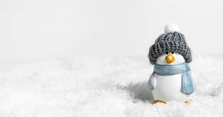 Christmas white snow background, panorama. Happy cute penguin in a winter hat on snowdrifts with hard shadows on the snow. Christmas or New Years concept. Bird penguin in a snowdrift. Bannerの写真素材
