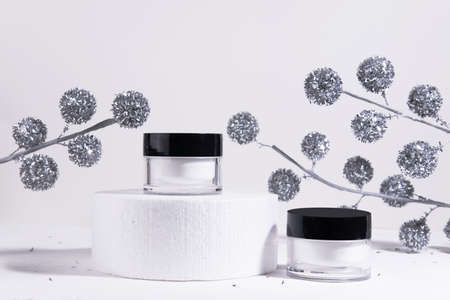 Christmas cosmetic white background. Mockup of moisturizer cosmetic product in a jar on a cylinder...