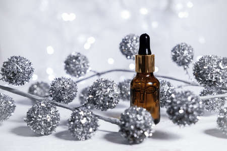 Christmas advertising cosmetic background. Dropper glass bottle mockup. Bottle with cap. Cosmetology and beauty concept. Winter season cosmetics. Gifts for Christmas or New Year.の写真素材