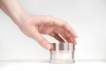 Female hand holding mockup unbranded plastic cosmetic tube. Bottle for cosmetic cream, toiletry. Skin care and beauty concept with copy space. Bottle for professional cosmetics product, on white background.の写真素材