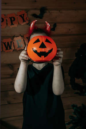Halloween kids. Cute little boy, child in suit with orange Jack O Lantern candy bucket. Happy...