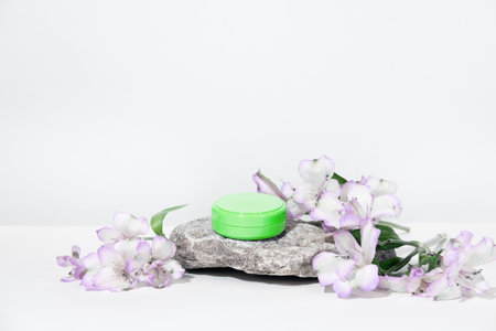 A mock up white jar of cream on a natural stone podium pedestal, on a white table, with plant, flowers, with hard shadows. Stylish look of the product, identity.の写真素材