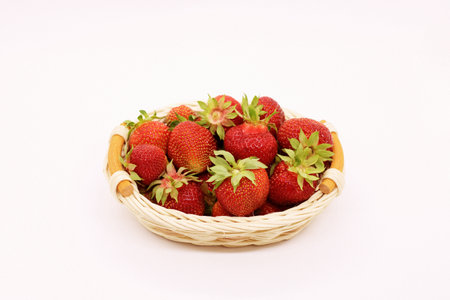 composition of ripe strawberries on a white background in a wicker basketの写真素材