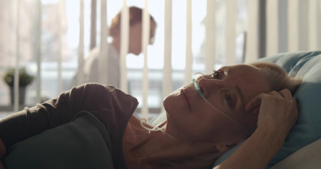 Sick aged woman with oxygen tube lying hospitalized in medical clinic.の写真素材
