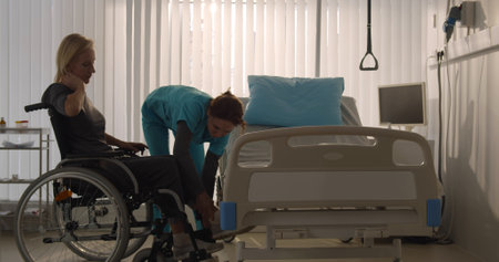 Nurse taking senior woman patient in wheelchair at hospital wardの写真素材