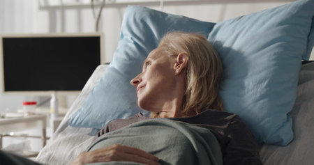 Portrait of senior sick woman patient lying in hospital bed