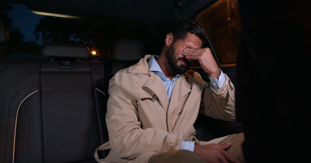 Young depressed businessman crying on backseat of carの写真素材
