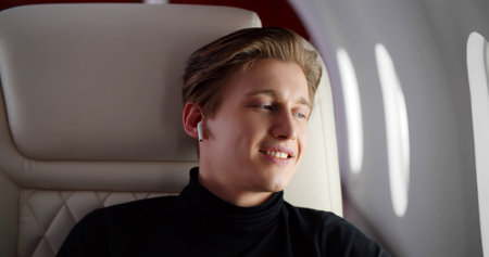 Portrait of handsome young man wearing earphones sleeping while enjoying first class flight in planeの写真素材