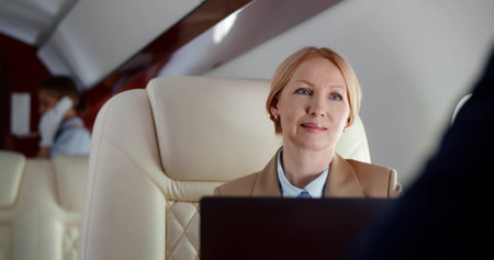 Businessman and businesswoman talking while sitting in private jetの写真素材