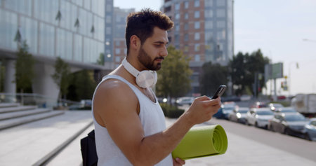 Side view of indian man using smartphone app after training outdoorsの写真素材