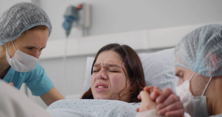 Close up of young woman giving birth in hospital delivery bookの写真素材