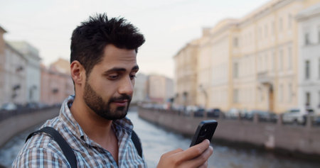 Young indian tourist man smiling using smartphone at cityの写真素材