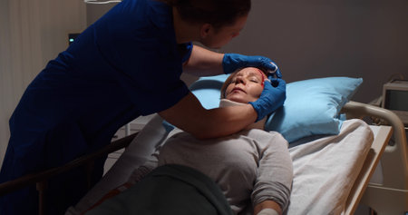 Mae nurse washing wound of unconscious aged female patient lying in hospital bedの写真素材