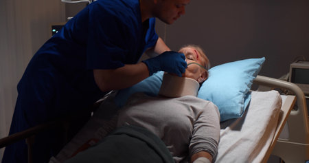 Nurse putting oxygen mask on elderly injured woman patient lying in hospital bedの写真素材