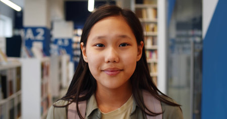 Asian girl student looking at camera walking in bookstoreの写真素材
