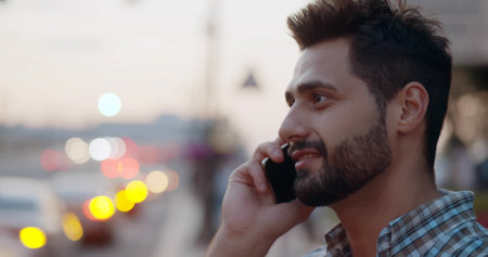 Bokeh shot of happy man talking on smartphone outdoorsの写真素材