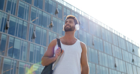 Low angle view of indian man listening music with wireless headphones outdoor after gymの写真素材