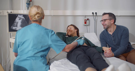 Mature pregnant couple smiling looking at the sonogram results on ultrasound scanner monitorの写真素材