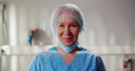 Confident senior female nurse wearing blue scrubs uniform looking at cameraの写真素材