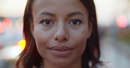 Bokeh close-up portrait of smiling woman on street.の写真素材
