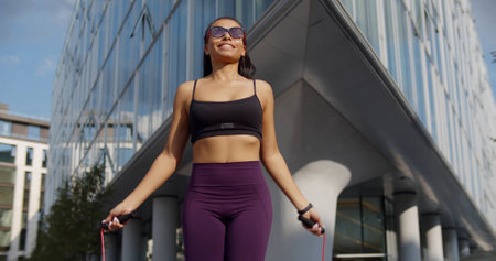 Fit mixed-race female practicing cardio workout with skipping rope outdoorsの写真素材