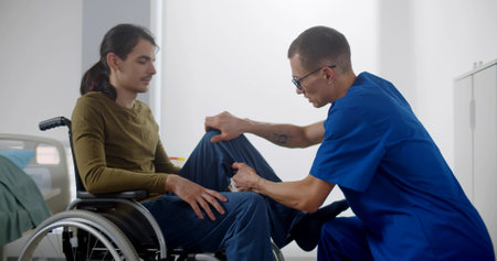 Rehabilitation doctor massaging leg of patient in wheelchairの写真素材