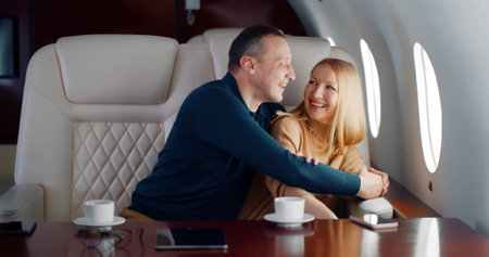 Happy middle-aged couple laughing and enjoying view in airplane windowの写真素材
