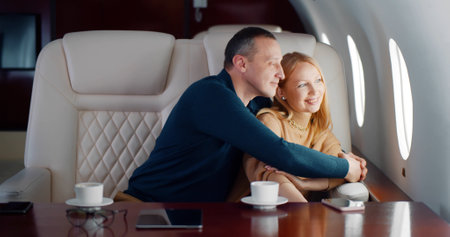 Happy mature couple looking through window in airplaneの写真素材