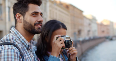 Diverse couple of tourists taking photo on vintage camera in cityの写真素材