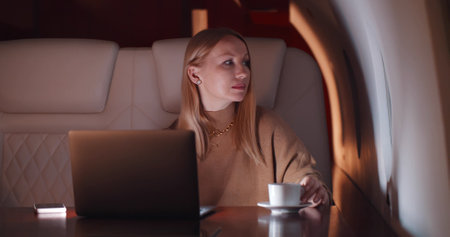 Elegant businesswoman working on laptop flying first class late at nightの写真素材