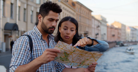 Happy multiethnic couple tourists sightseeing city with mapの写真素材