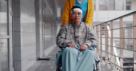Nurse pushing wheelchair with wounded soldier outdoors army hospitalの写真素材