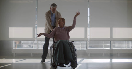 Senior man pushing wheelchair with wife sitting and dancingの写真素材