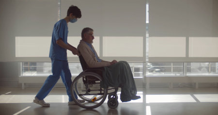 Nurse wearing face medical mask pushing wheelchair with senior man patientの写真素材