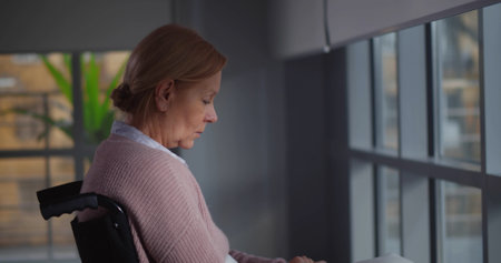 Sad elderly woman seated in wheelchair cryingの写真素材