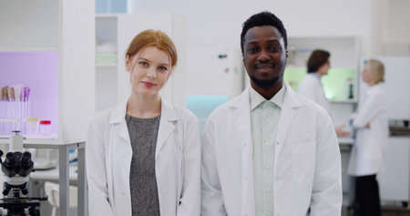 Portrait of multiethnic young scientists smiling at camera in modern laboratoryの写真素材