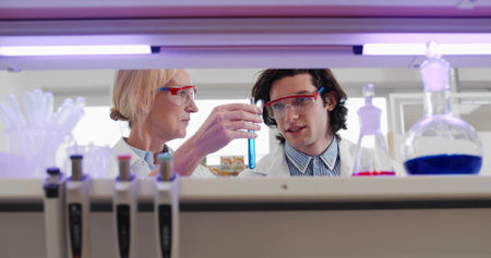 Two scientists holding test tube with blue liquid sample in chemistry labの写真素材