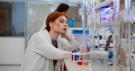 Portrait young woman scientist sleeping feeling tired working in medical laboratoryの写真素材