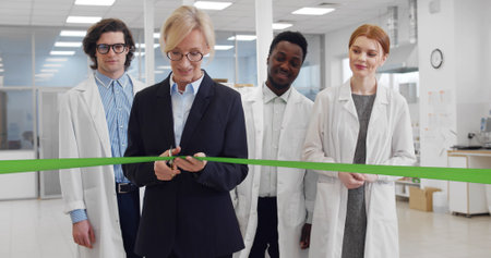 Mature businesswoman cutting ribbon opening new biochemical laboratory