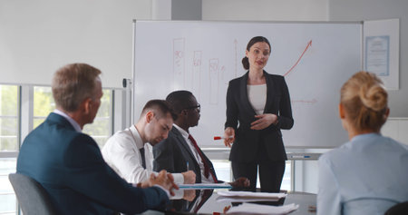 Businesswoman showing results to group of business people at meetingの写真素材