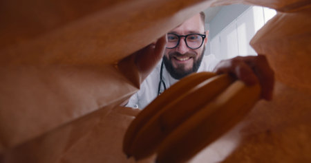 View from inside paper bag of young male doctor taking bananas for lunch