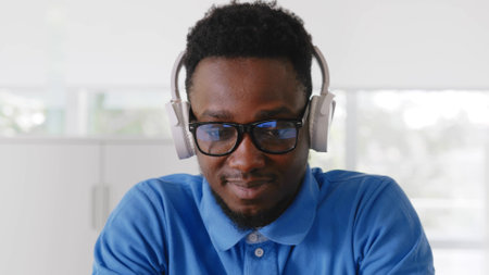 Close up of african businessman with headphones and computer working at officeの写真素材