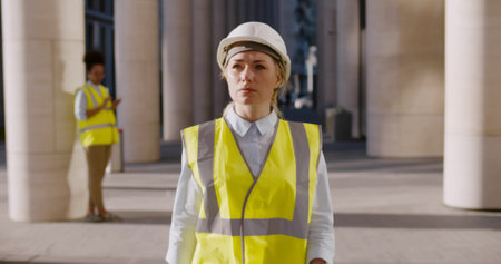 Young civil engineer in hardhat walking outside modern buildingの写真素材