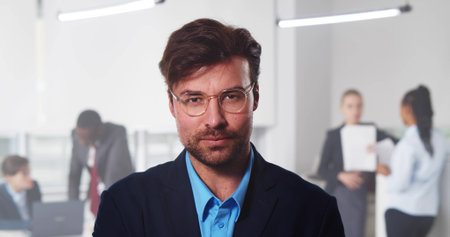 Handsome young businessman standing in office in front of his team