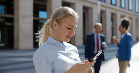 Successful businesswoman using app technologies on smartphone during lunch break outside officeの写真素材