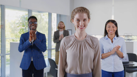 Portrait of multi-cultural business team applauding to young female leader in office