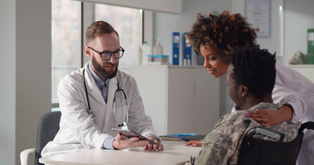Disabled soldier in wheelchair with wife visiting doctor discussing treatmentの写真素材