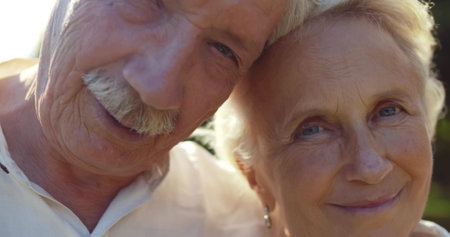 Close up of happy senior couple in love looking at camera at park.