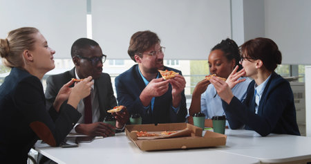 Young international business team having lunch break in office eating pizza togetherの写真素材